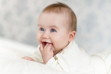 Odasındaki yatakta emekleyen bir bebeğin portresi.