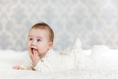 Odasındaki yatakta emekleyen bir bebeğin portresi.
