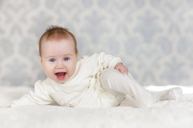 Odasındaki yatakta emekleyen bir bebeğin portresi.