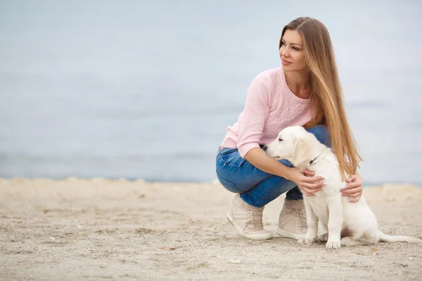 A young woman near the sea with a puppy Retriever — Stok fotoğraf