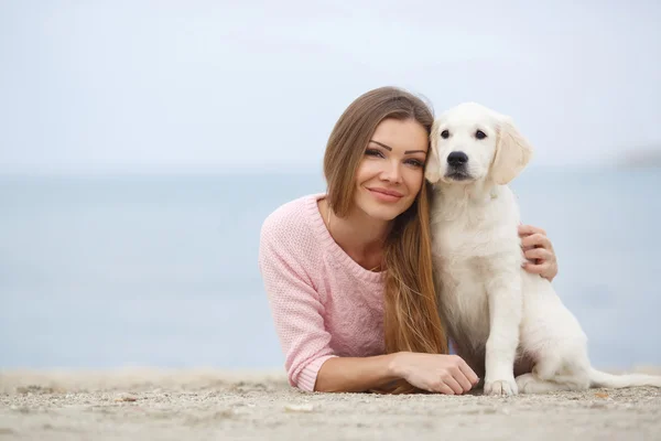 A young woman near the sea with a puppy Retriever — Stockfoto