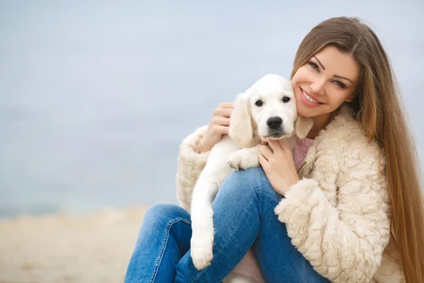 A young woman near the sea with a puppy Retriever — Zdjęcie stockowe