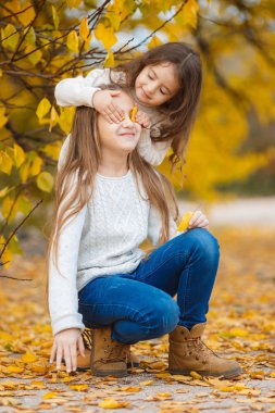 Girls play in yellow park in the fall