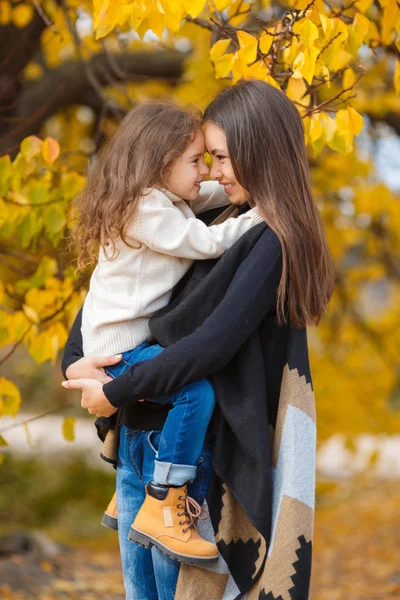 Счастливая мать и дочь гуляют в парке осенью — стоковое фото