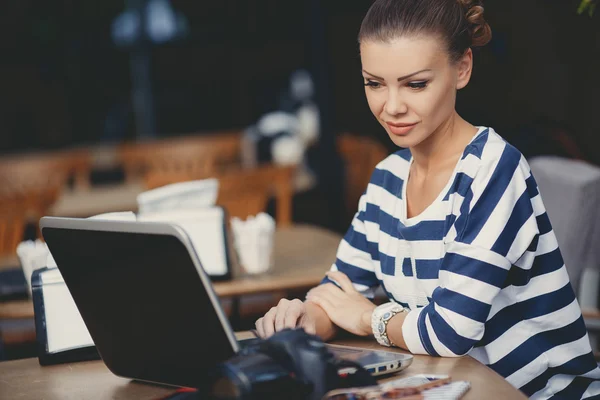 The young female photographer behind a little table in cafe — Stock Photo, Image