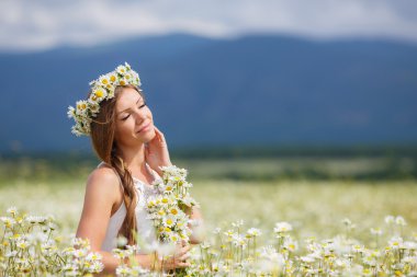 Beautiful young woman in a field of blooming daisies