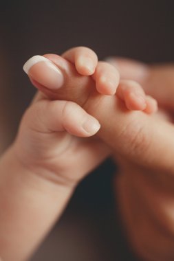 Yeni doğmuş bebek annesinin parmağını tutuyor.