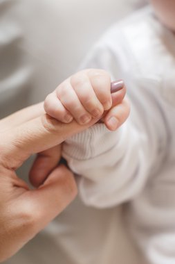 Yeni doğmuş bebek annesinin parmağını tutuyor.