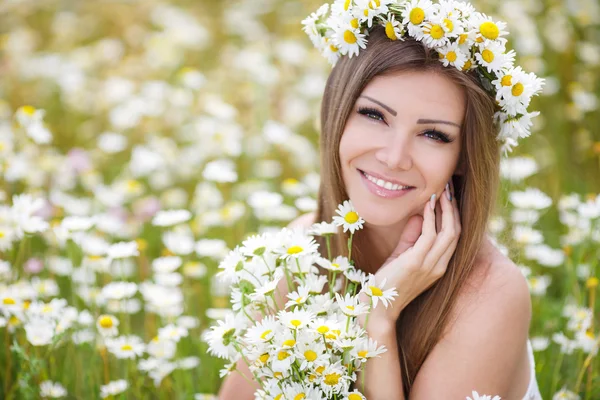 Mulher bonita em um campo de margaridas florescendo — Fotografia de Stock