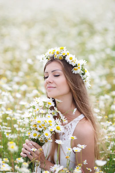 Beautiful young woman in a field of blooming daisies — ストック写真