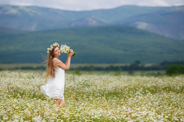 Mulher bonita em um campo de margaridas florescendo — Fotografia de Stock