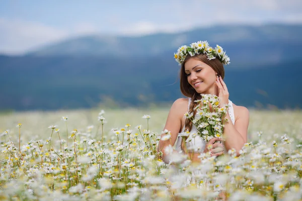 Beautiful young woman in a field of blooming daisies — Stock fotografie