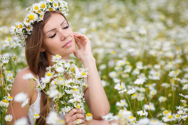 Mulher bonita em um campo de margaridas florescendo — Fotografia de Stock