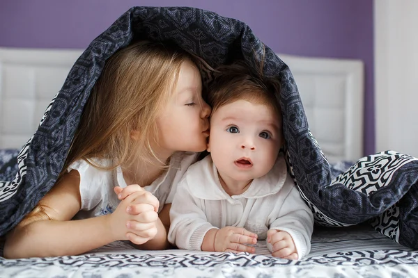 Two sisters lying on the bed under the blanket — Stock fotografie