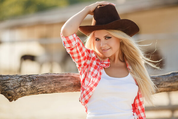 Portrait of a beautiful woman in a big cowboy hat on ranch