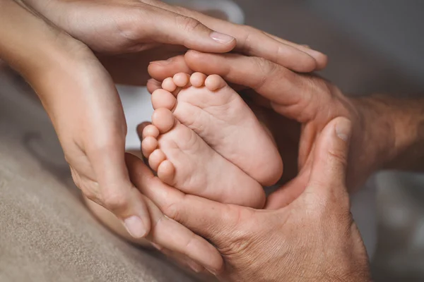 Los pies de los niños en manos de la madre y el padre . —  Fotos de Stock