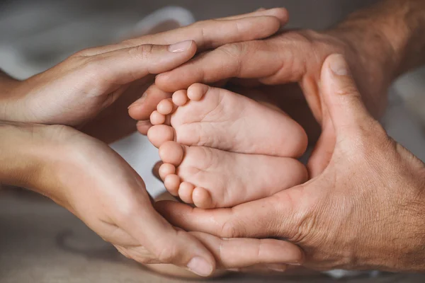 Children's feet in hands of mother and father. — Stock Fotó