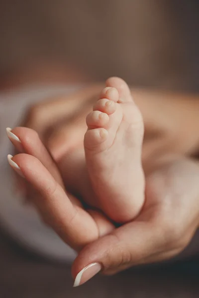 Las piernas de los niños en la palma de la madre — Foto de Stock