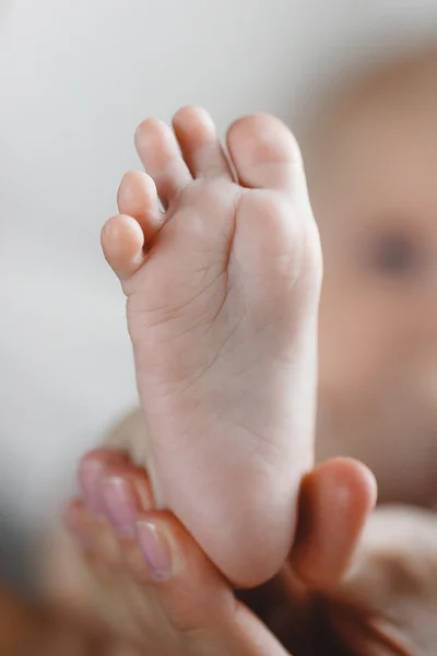 Las piernas de los niños en la palma de la madre — Foto de Stock