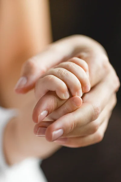 Yeni doğmuş bebek annesinin parmağını tutuyor. — Stok fotoğraf