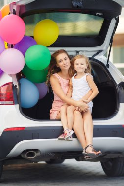 Mom and daughter in a car with balloons