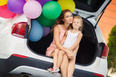 Mom and daughter in a car with balloons
