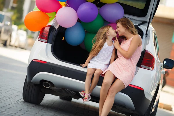 Maman et fille dans une voiture avec des ballons — Photo