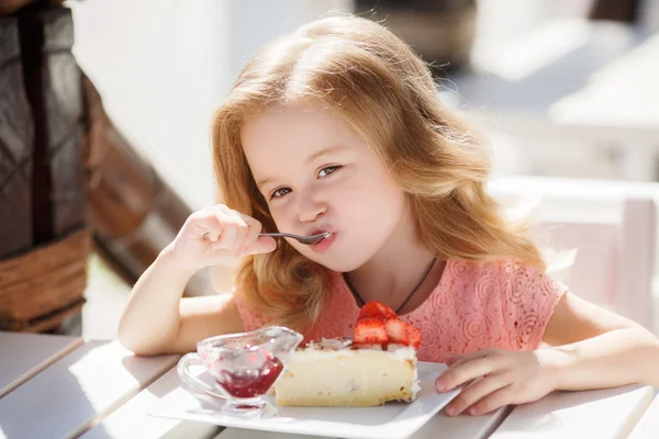 Menina comendo bolo com morangos no café de verão — Fotografia de Stock