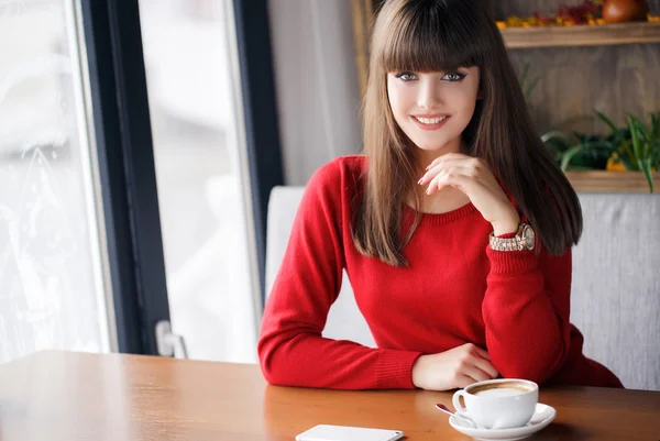 Menina com uma xícara de chá quente em uma mesa em um café — Fotografia de Stock