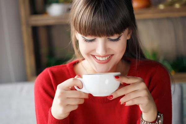 Menina com uma xícara de chá quente em uma mesa em um café — Fotografia de Stock