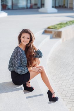 Portrait of a beautiful young woman, sitting on the stairs in the city.