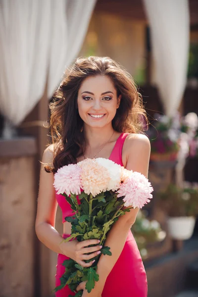 Beautiful brunette with a bouquet of pink flowers — Stok fotoğraf