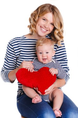 Happy mother and her little son holding a pillow in the form of red hearts.