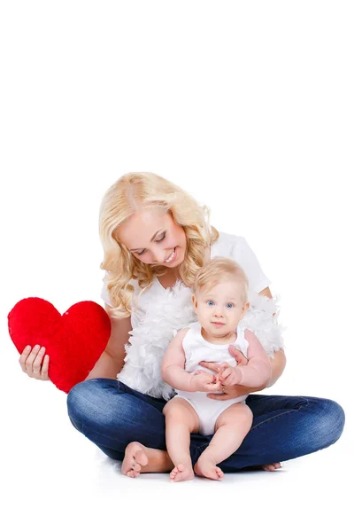 Happy mother and her little son holding a pillow in the form of red hearts. — Zdjęcie stockowe