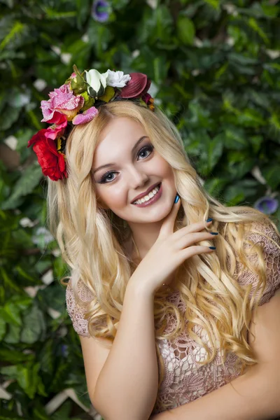 Süßes lächelndes blondes Mädchen mit einem Kreis aus Blumen — Stockfoto