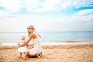 Anne ile bebek kumsalda oynarken. arka görünüm.