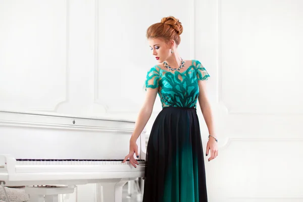 ファッションの若い可愛い赤毛の女性がグランド ピアノを弾く — ストック写真