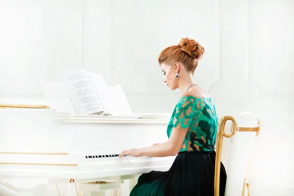 美しい若い魅力的な女性のドレスを再生ホワイト ピアノ — ストック写真
