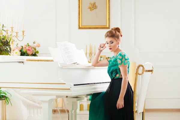 美しい若い魅力的な女性のドレスを再生ホワイト ピアノ — ストック写真