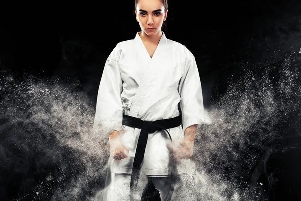 Portrait of sporty karate and taekwondo woman in white kimono with black belt on dark background. — Stock Photo, Image