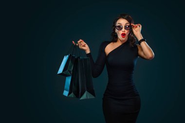 Kara Cuma mağaza satış konsepti. Güneş gözlüklü kız, elinde büyük bir çanta tutuyor. Kara arka planda, cuma günü alışverişte..