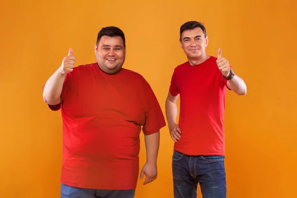 穿着红T恤的又胖又瘦的家伙。两个肤色不同的男人被隔离在一个黄色的背景上。Ectomorph和endomorph — 图库照片