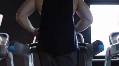 Spor salonunda koşu bandında koşan bir sporcu. Fitness ve egzersiz motivasyonu