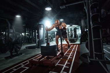 Vücut geliştiren sporcu spor salonunda çalışıyor. Kızakla güçlü ve formda bir adam eğitimi. Spor ve spor motivasyonu. Bireysel spor eğlencesi.