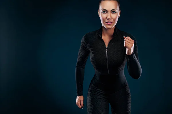 Atleta corridore e velocista, corre su sfondo nero indossando l'abbigliamento sportivo e le cuffie. Fitness e motivazione sportiva. — Foto Stock