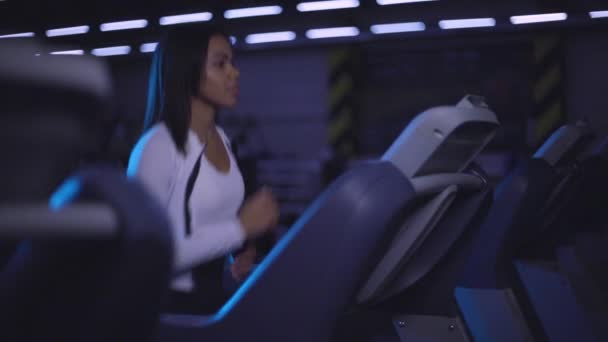 Chica negra corre en una cinta de correr. Una mujer bonita corriendo en el gimnasio. Movimiento lento. — Vídeo de stock
