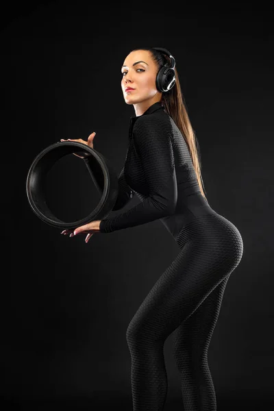 Kvinnlig idrottsman i svarta sportkläder. ung gymnastik flicka med pilates fitness ring hjul på svart bakgrund i yoga studio klassrum. — Stockfoto