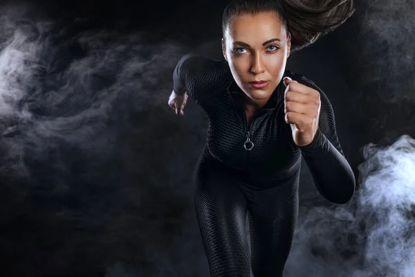 Forte velocista atletica donna, corre su sfondo nero indossando lo sportswear. Fitness e motivazione sportiva. Concetto corridore. — Foto Stock