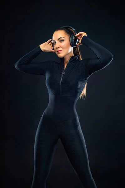 Sport concept. Sportieve fitte vrouw, atleet met hoofdtelefoon maken fitnessoefeningen op zwarte achtergrond. — Stockfoto