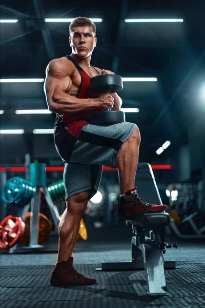 Testépítő atléta férfi pumpálja fel az izmokat a tornateremben. Brutális erős izomagyú srác fitnesz edzésen. Testfelépítés koncepciója. — Stock Fotó